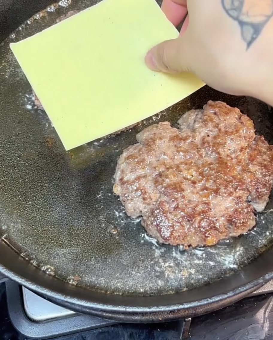 Käsige Rindfleisch-Patties in einer heißen Gusseisenpfanne.