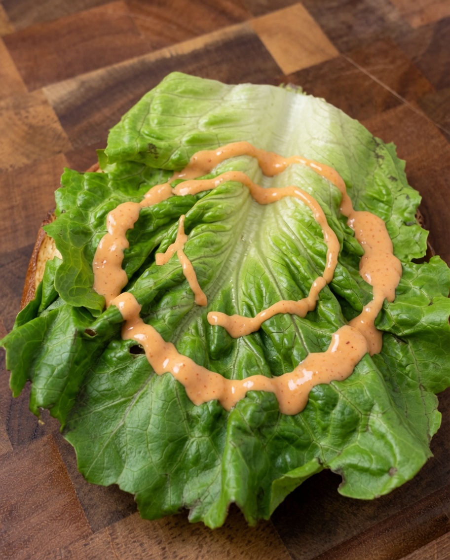 Frischer Burgeraufbau mit Salat, Zwiebeln und Tomatenschichten.