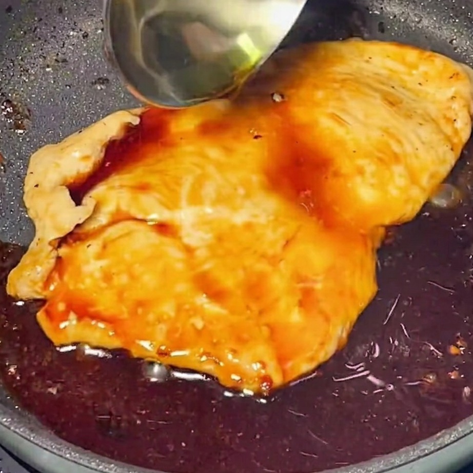 Reiche, glänzende Teriyaki-Sauce, die über goldbraunes Hähnchen in einer Pfanne gegossen wird.