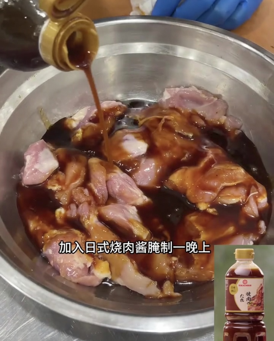 Entbeinte Hähnchenschenkel, die in einer Edelstahlschüssel in dunkler japanischer Teriyaki-Soße baden.