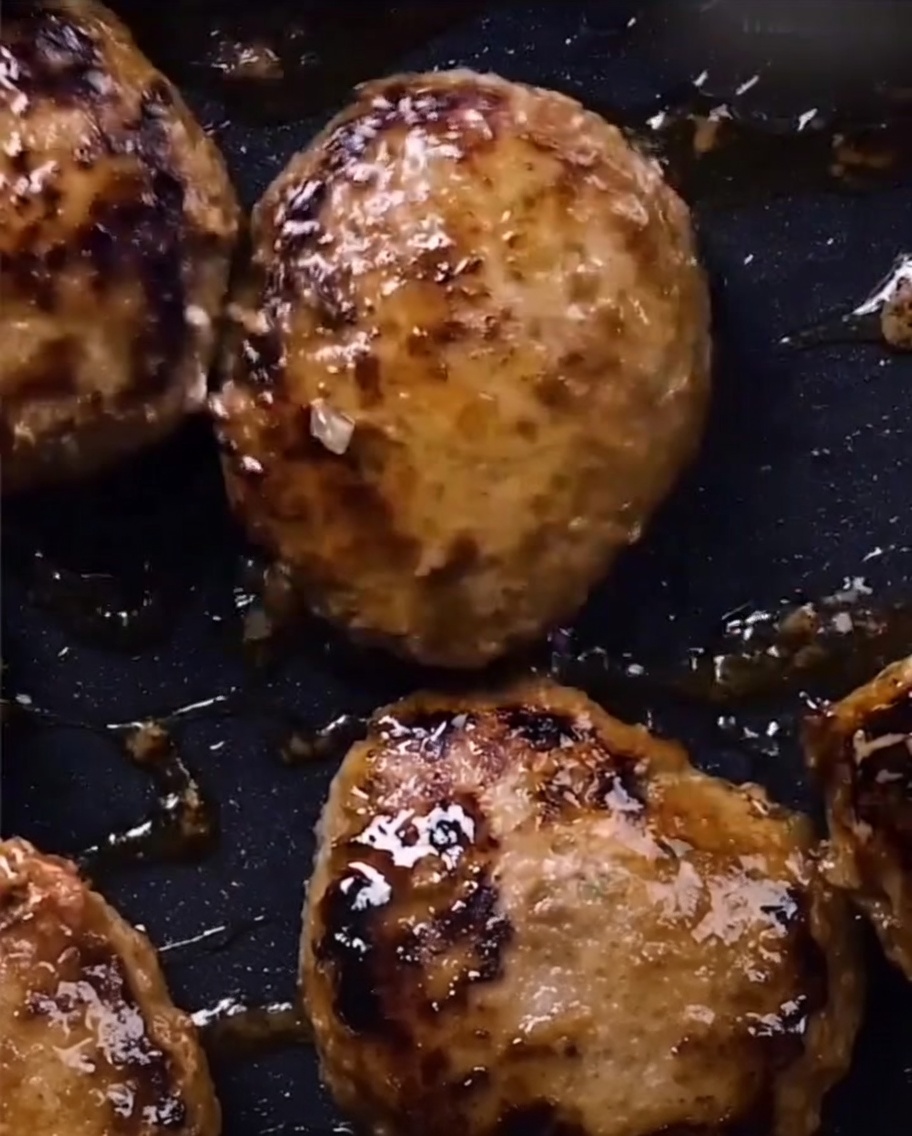 Glänzende, mit Teriyaki-Sauce überzogene Fleischsteaks in der Pfanne.