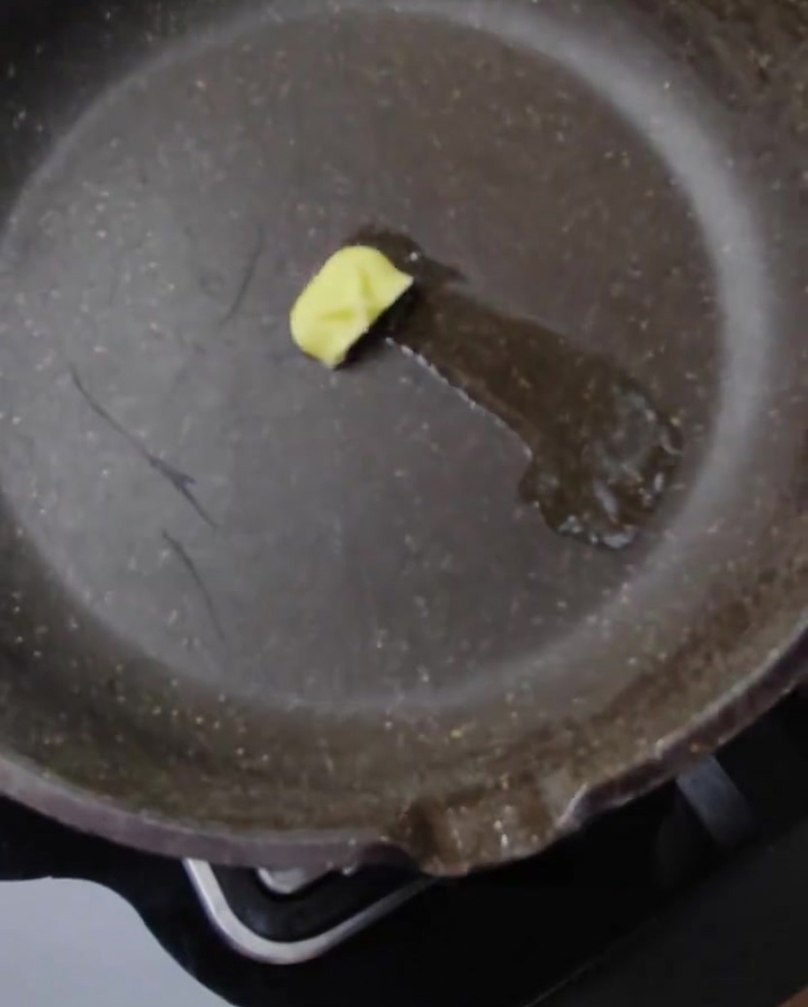 Burgerbrötchenhälften werden in einer Pfanne mit geschmolzener Butter getoastet.