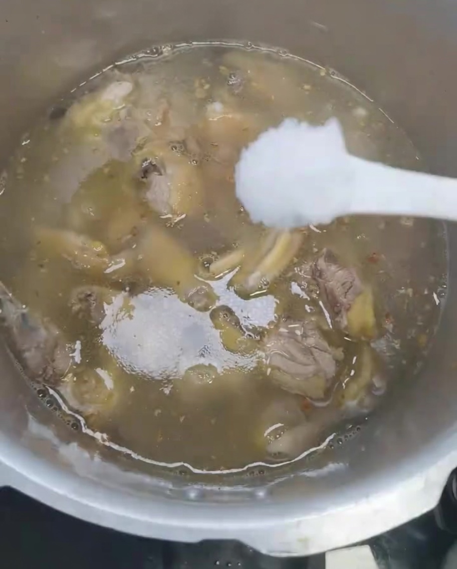 Salz wird zur Hühnersuppe im Schnellkochtopf gegeben.