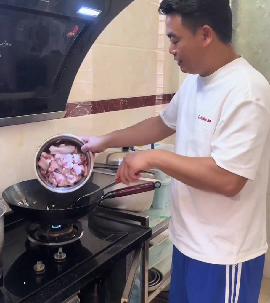 Hähnchenstücke, die mit gehacktem Ingwer in einem heißen, glänzenden Wok angebraten werden.