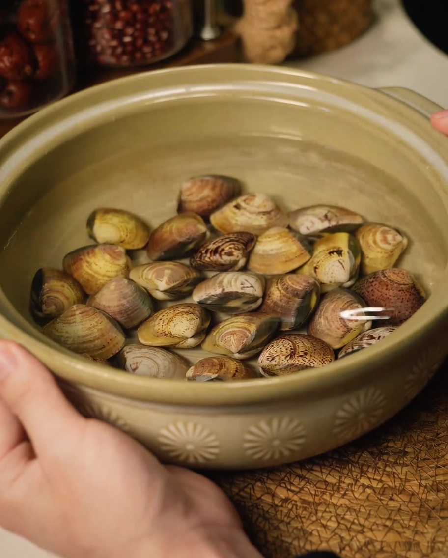 Frische Muscheln in einer Keramikschüssel mit Wasser, um Sand zu entfernen.