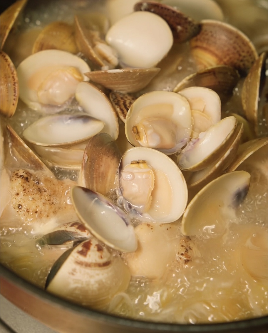 Frische Muscheln werden zur Hühnersuppe in den Topf gegeben.