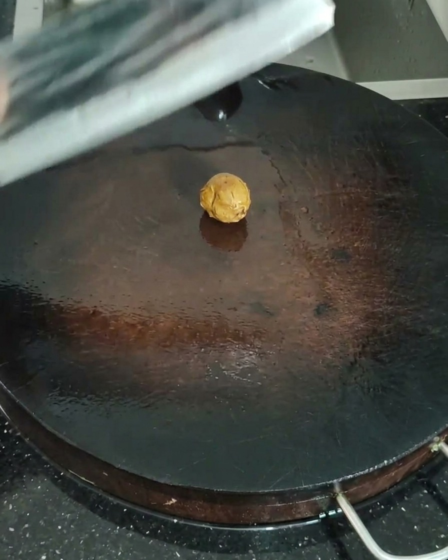 Nahaufnahme von Sand-Ingwer, der mit einem Fleischbeil auf einem Holzbrett zerdrückt wird.