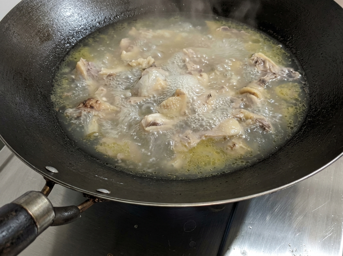 Eine köchelnde Hühnersuppe, zu der Salz hinzugefügt wird.