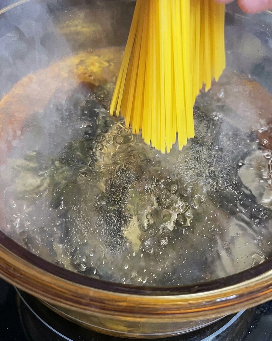 Spaghetti werden in einen großen Topf mit kochendem Salzwasser gegeben.