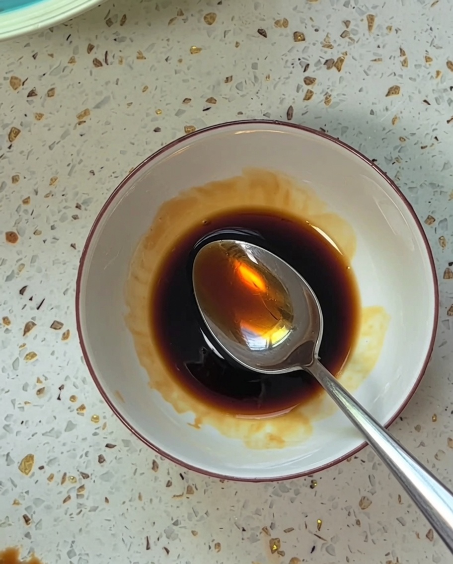 Zutaten werden in einer kleinen weißen Schüssel zu einer braunen, würzigen Sauce verrührt.