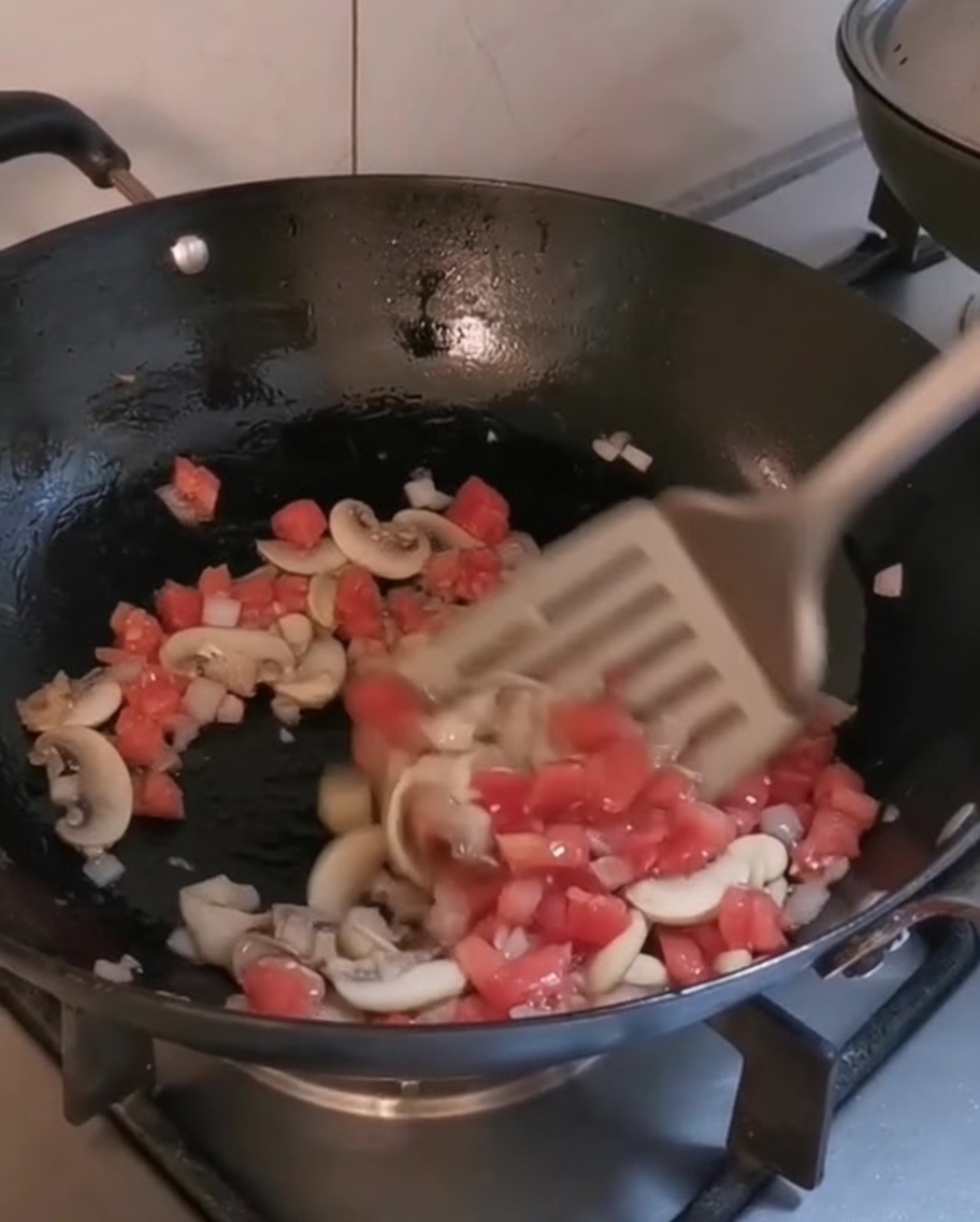 Gehacktes Gemüse und Pilze garen in einem heißen Wok mit Olivenöl.