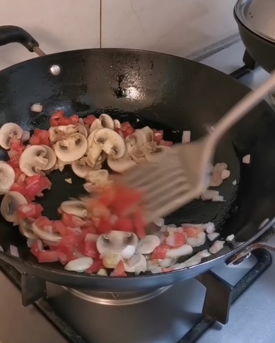 Gekochte Penne und Steakstreifen werden in einem Wok mit dem restlichen Gemüse vermengt.