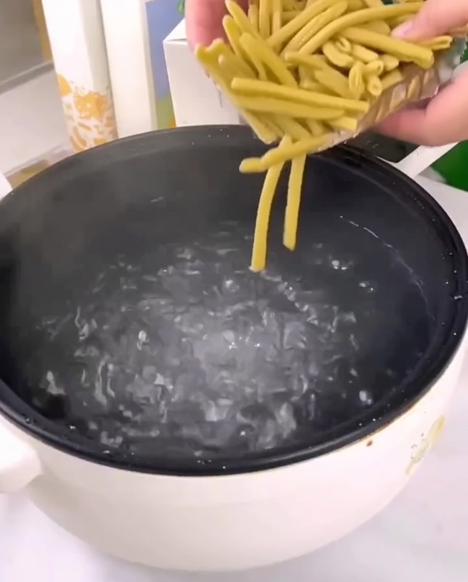 Getrocknete Hirse-Penne werden in einen Topf mit kochendem Wasser gegeben.