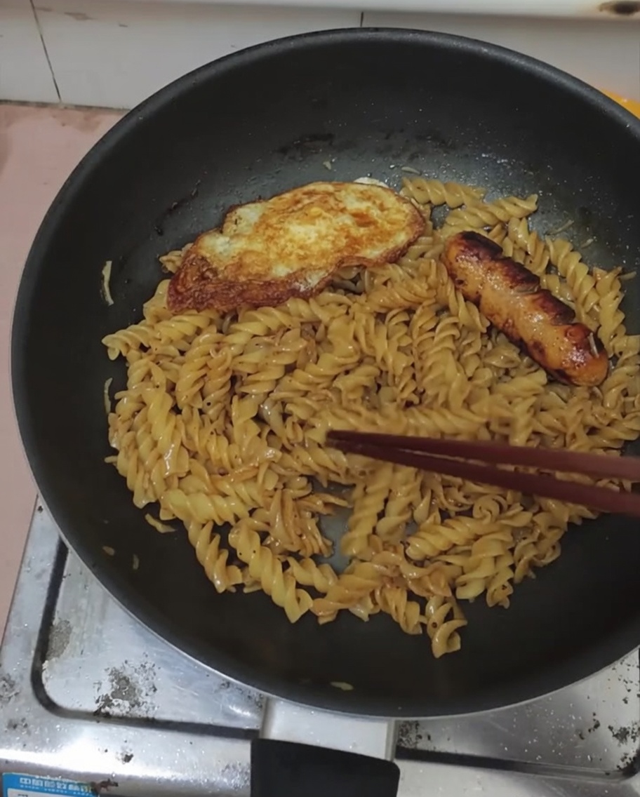 Spiegelei und Wurst auf einer Portion schwarze Pfeffer-Fusilli.