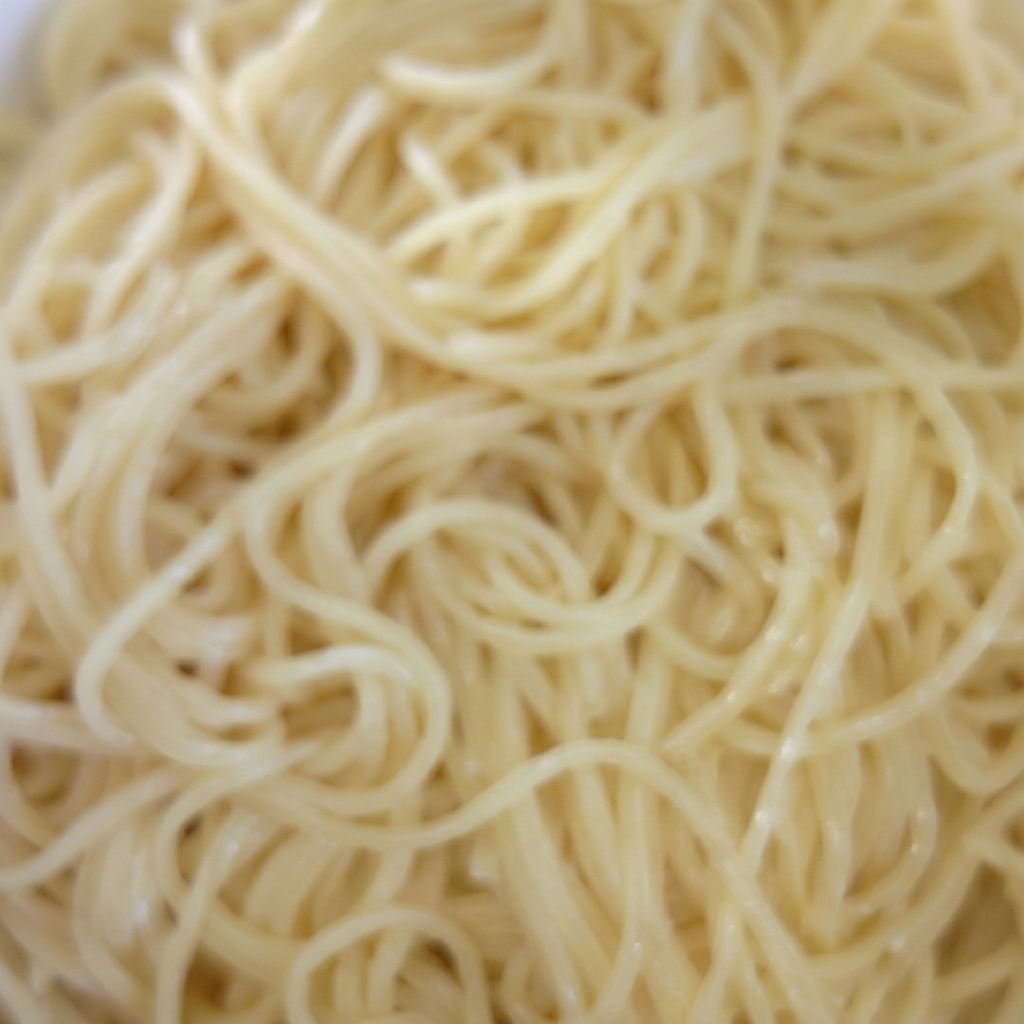 Gekochte Spaghetti in einer Schüssel werden mit Öl vermengt.