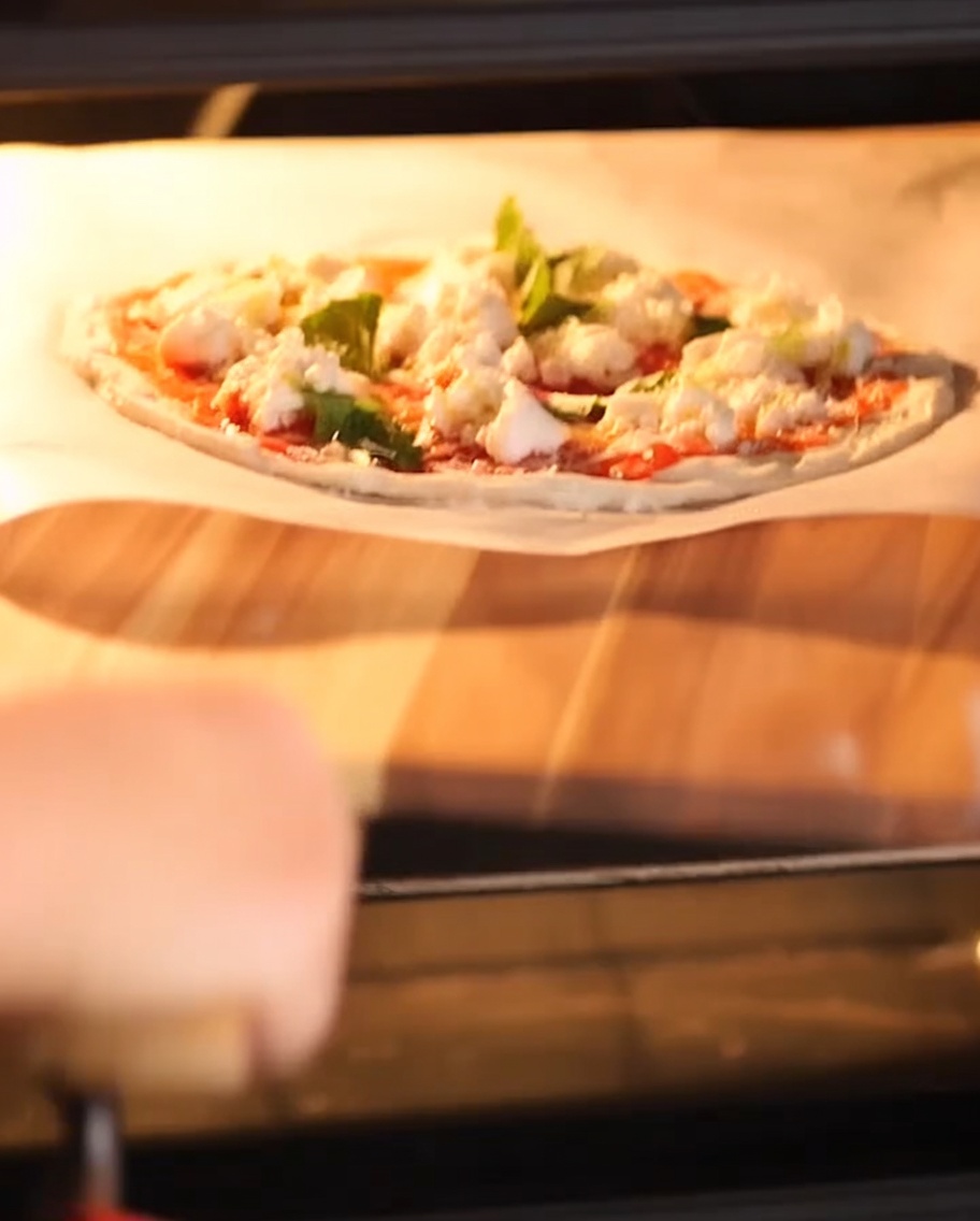 Der Rand der Pizza wirft Blasen und bräunt auf einem heißen Stein im Ofen.