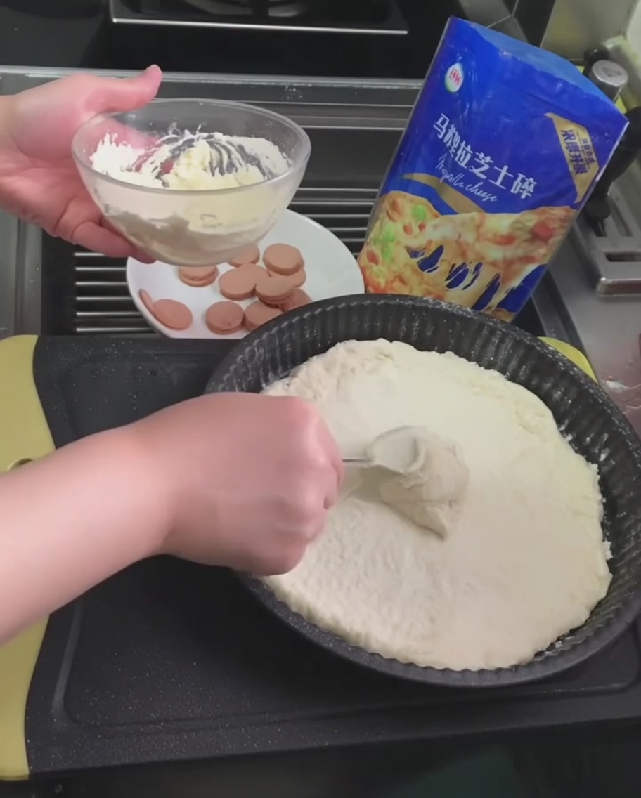 Weiße Trüffelsauce wird mit einem Löffel auf dem Pizzateig verteilt.
