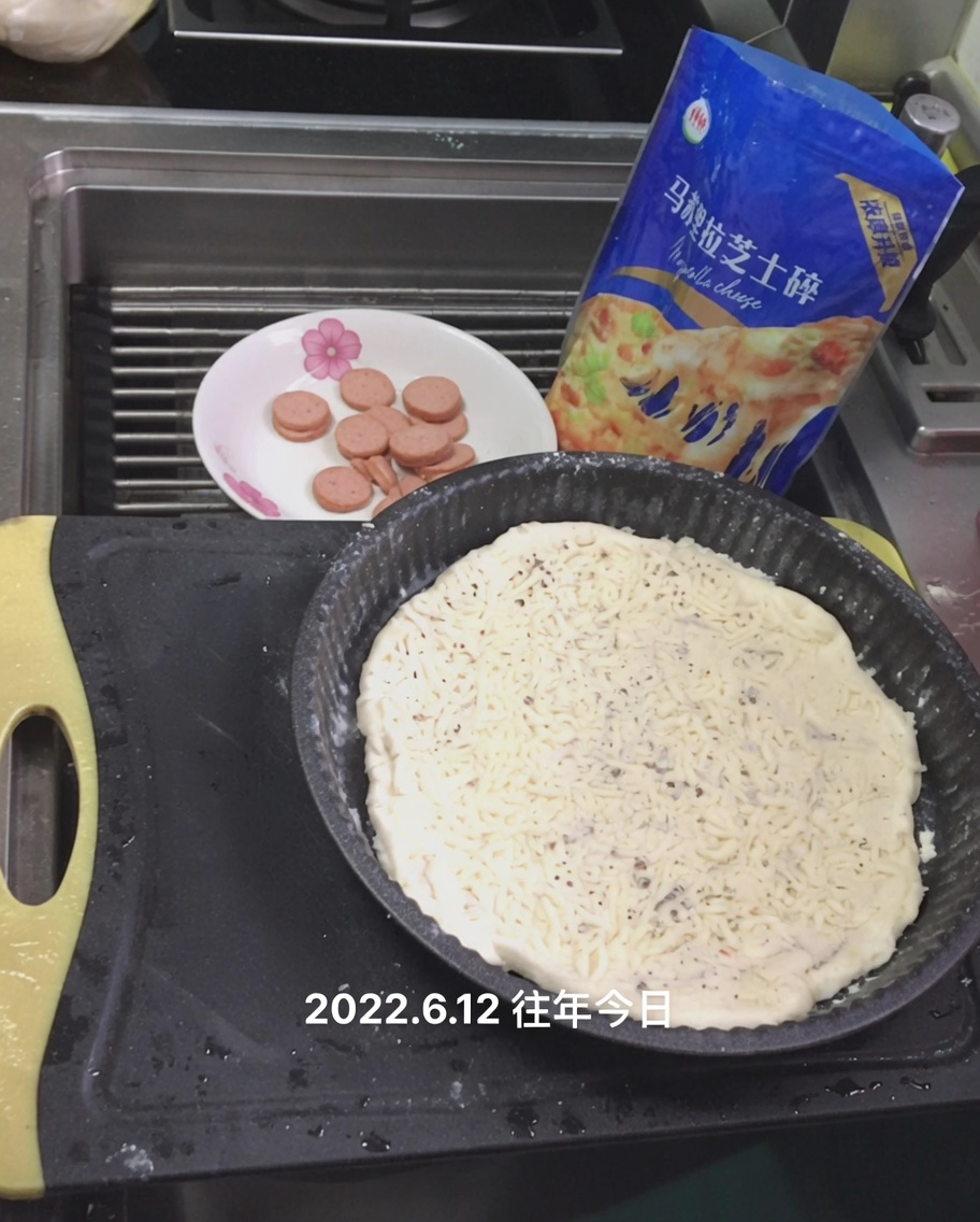 Geriebener Mozzarella wird über der weißen Sauce auf dem Pizzateig verstreut.
