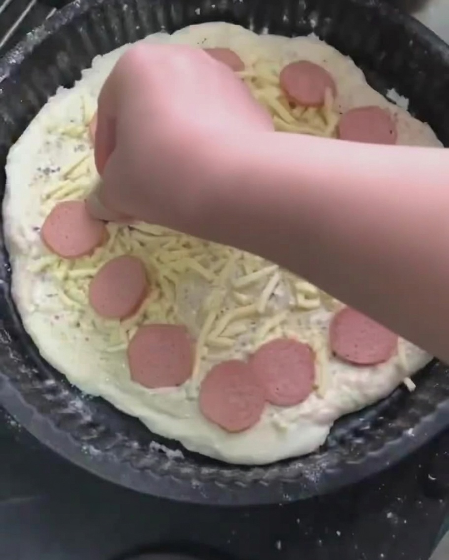 Wurstscheiben werden auf dem geriebenen Mozzarella platziert.