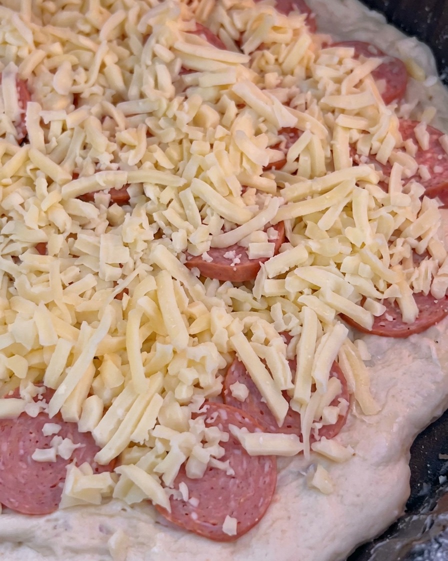 Die Pizza wird in den heißen Ofen geschoben, um den Backvorgang zu starten.