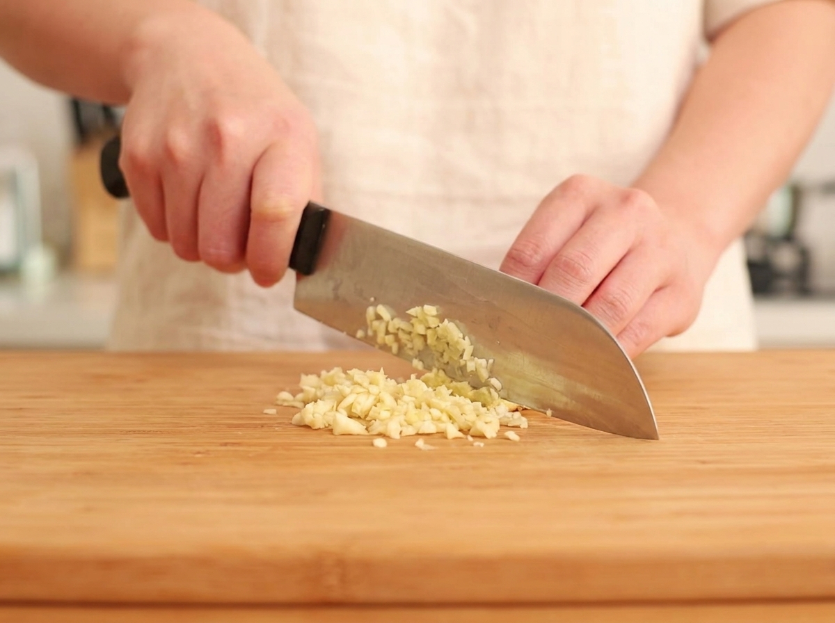 Frischer Ingwer und Knoblauch werden fein gehackt auf einer Holzoberfläche.