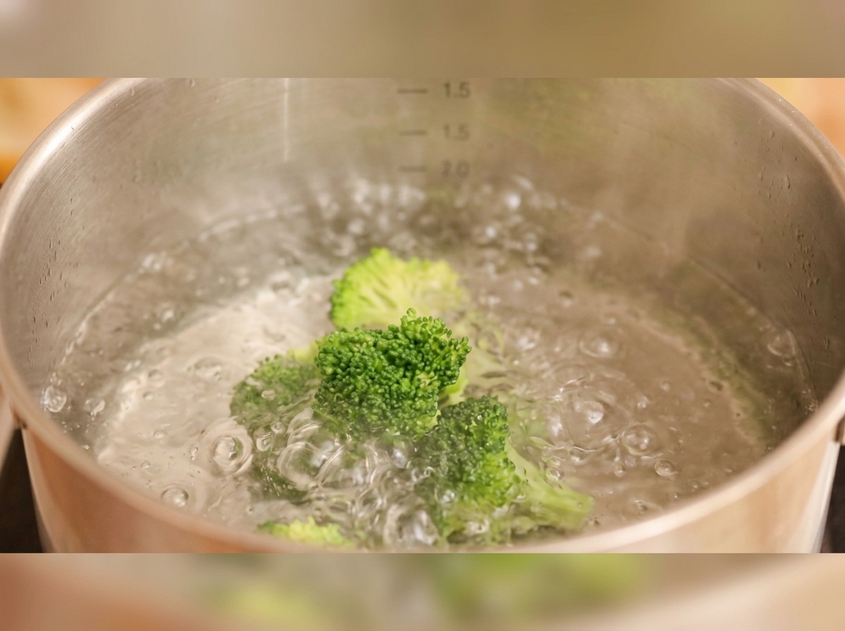 Brokkoli und dekorative Karottenscheiben kochen in einem Topf mit Wasser.