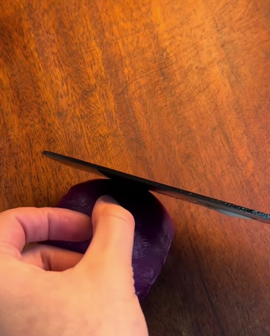 Ein scharfes Messer schneidet eine Zwiebel auf einem Holzbrett in feine Streifen.
