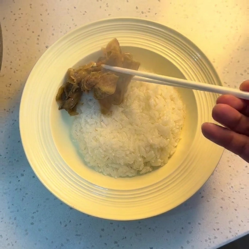 Stäbchen platzieren das gekochte Rindfleisch und die Zwiebeln auf einer Schüssel mit weißem Reis.