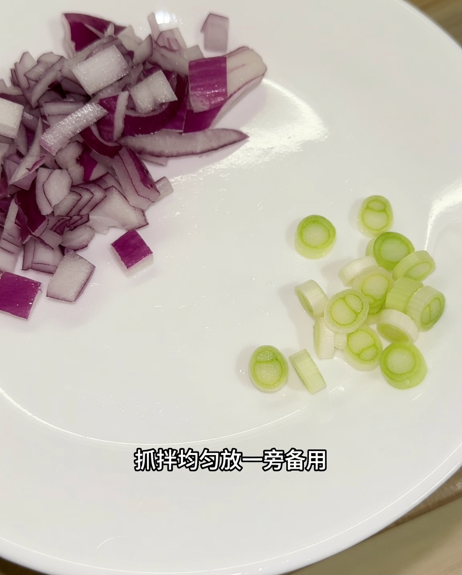Gehackte rote Zwiebel und geschnittene weiße Teile von Frühlingszwiebeln auf einem weißen Teller.