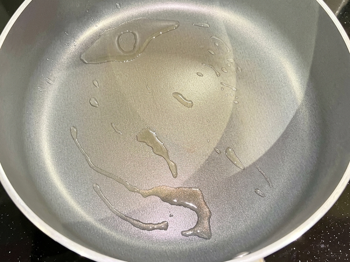 Gehackte rote Zwiebeln brutzeln in einer Pfanne mit heißem Speiseöl.