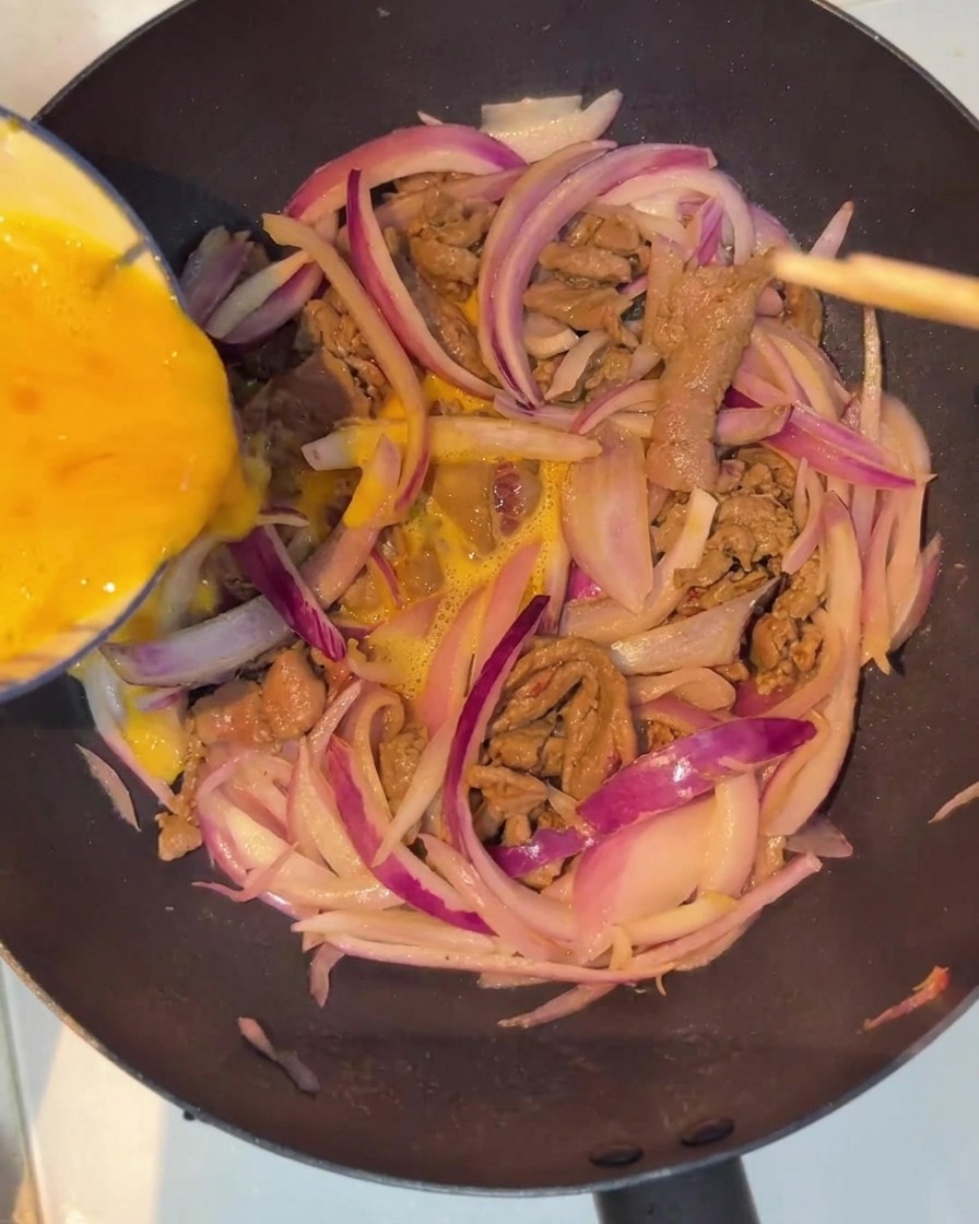 Eimasse wird über die Fleisch-Zwiebel-Mischung gegossen.