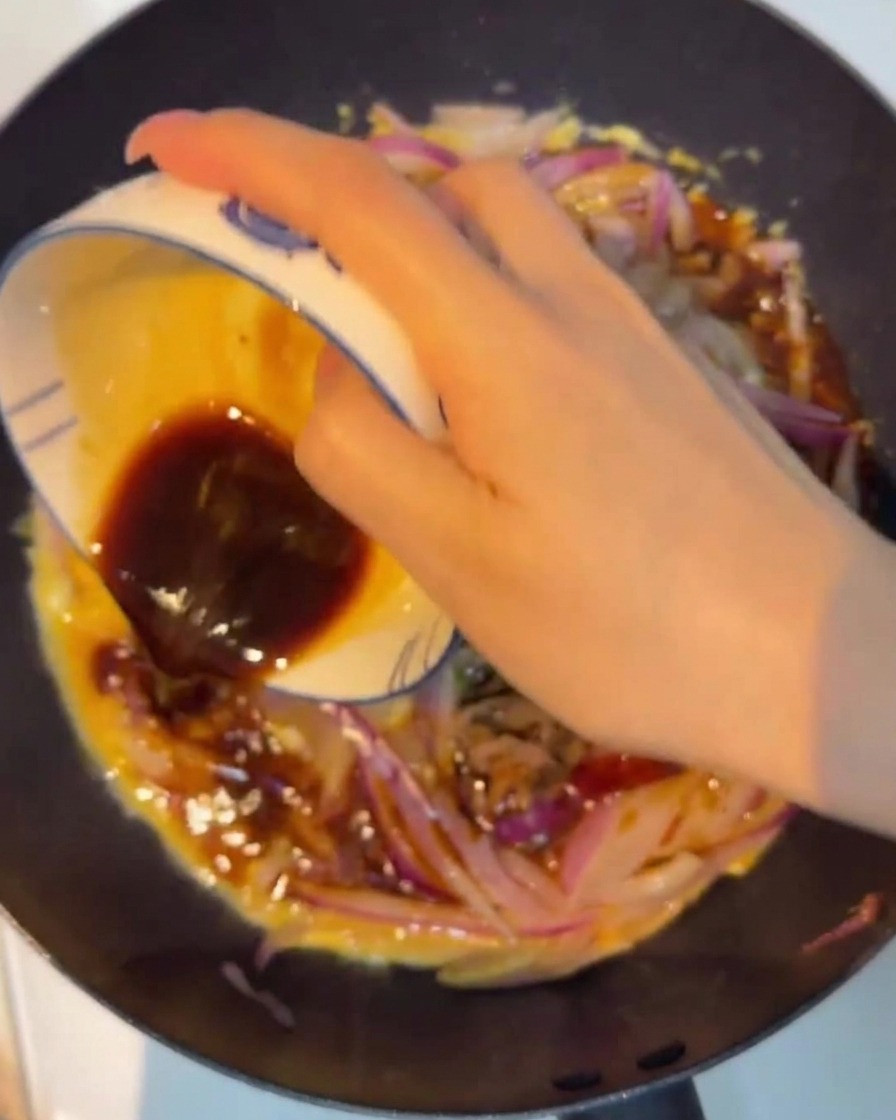 Dunkle Sauce wird über die Mischung geträufelt.