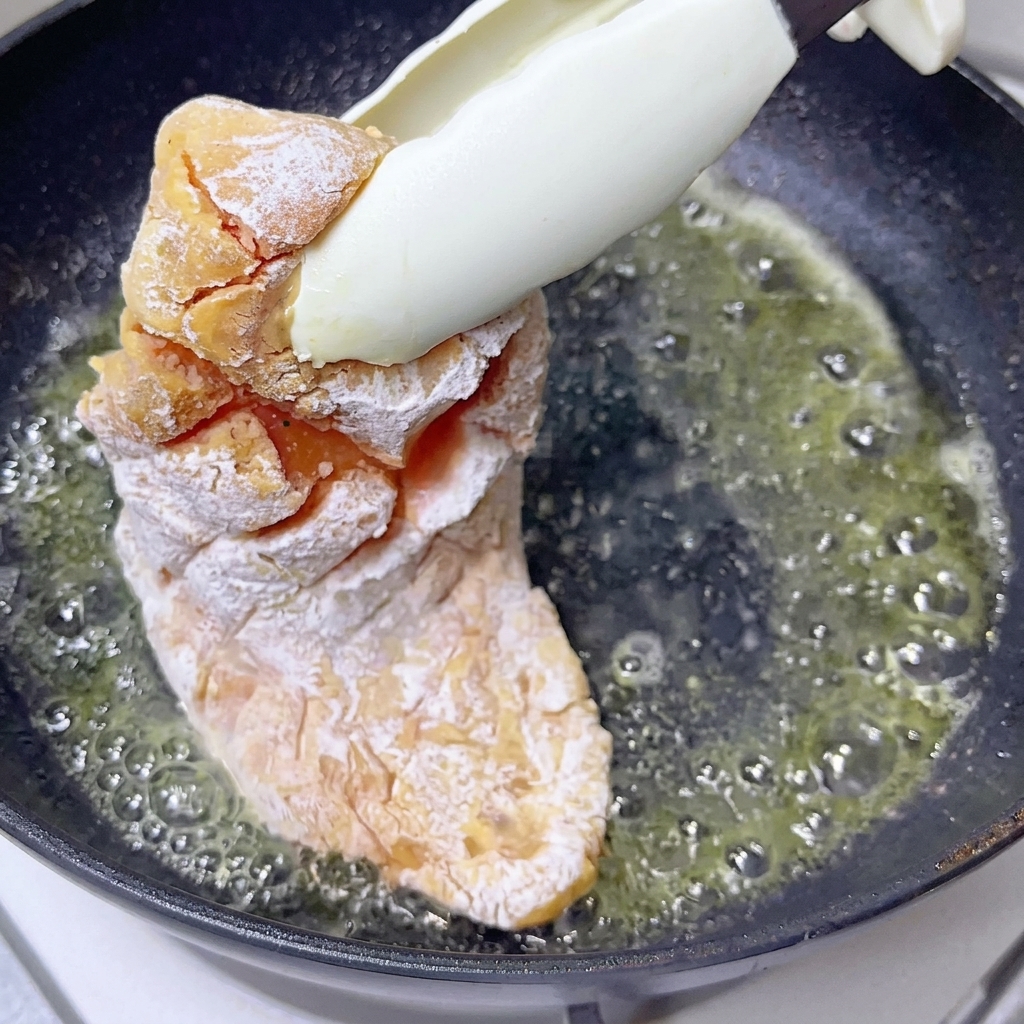 Ein Stück Butter schmilzt und blubbert leicht in einer heißen, dunklen Pfanne.