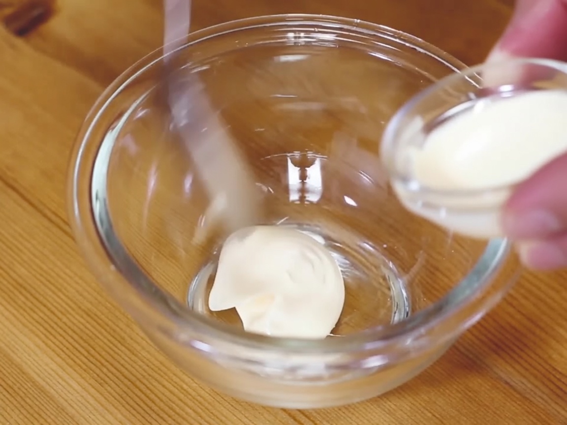 Eine kleine Schale mit einer cremigen Mischung aus Mayonnaise und Wasabi wird verrührt.