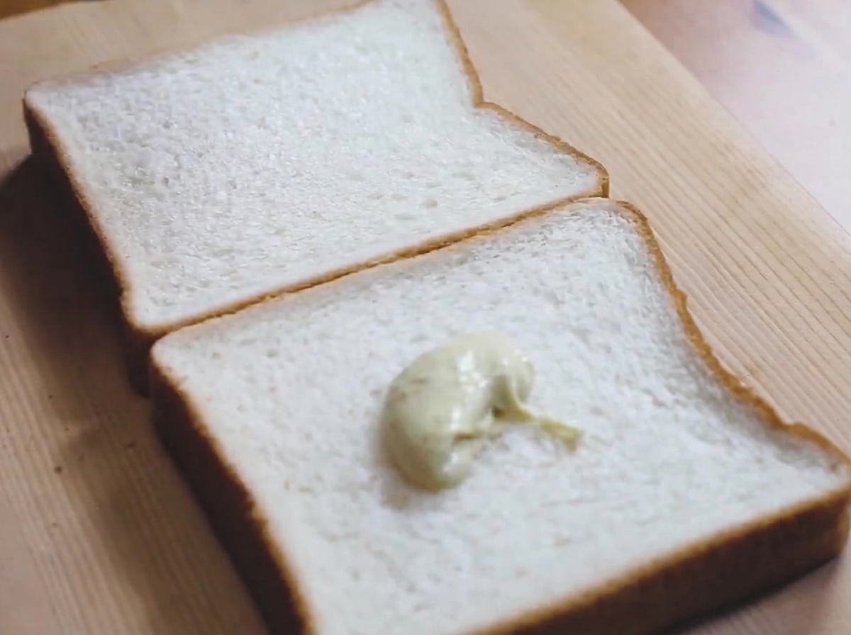 Ein Klecks hellgrüne Wasabi-Mayonnaise auf einer Scheibe Weißbrot.