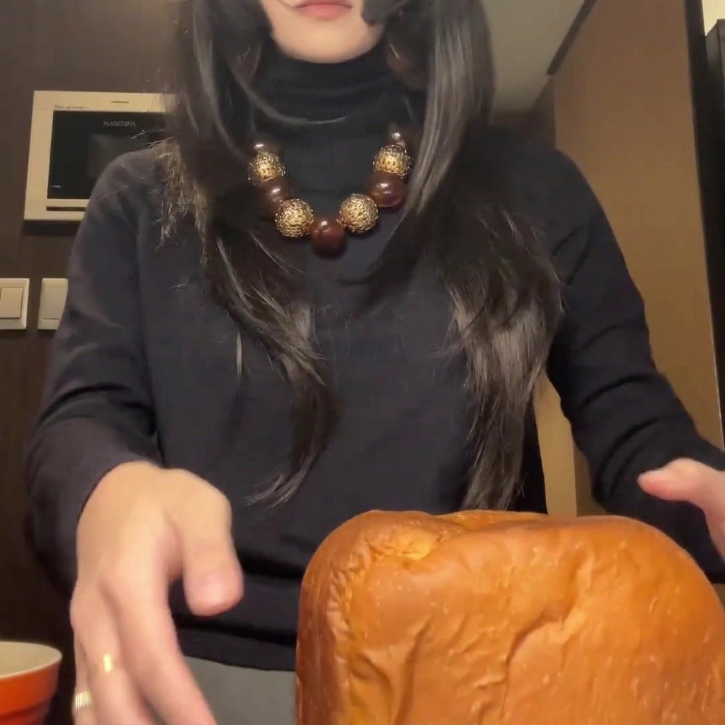 Ein frisch gebackener, goldbrauner Brotlaib, der auf einem Schneidebrett in dicke, gleichmäßige Scheiben geschnitten wird.