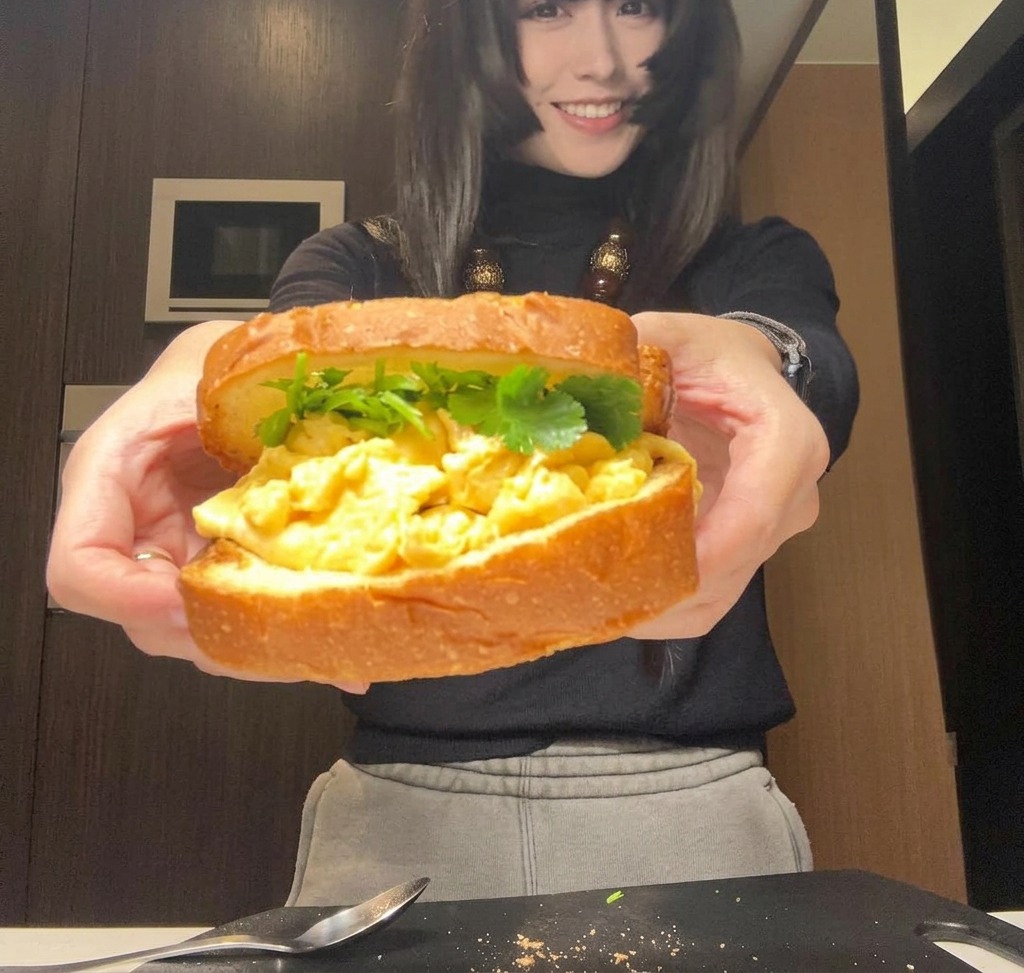 Ein komplett zusammengesetztes Sandwich, das in zwei Händen gehalten wird, bereit zum Einwickeln oder Aufschneiden.