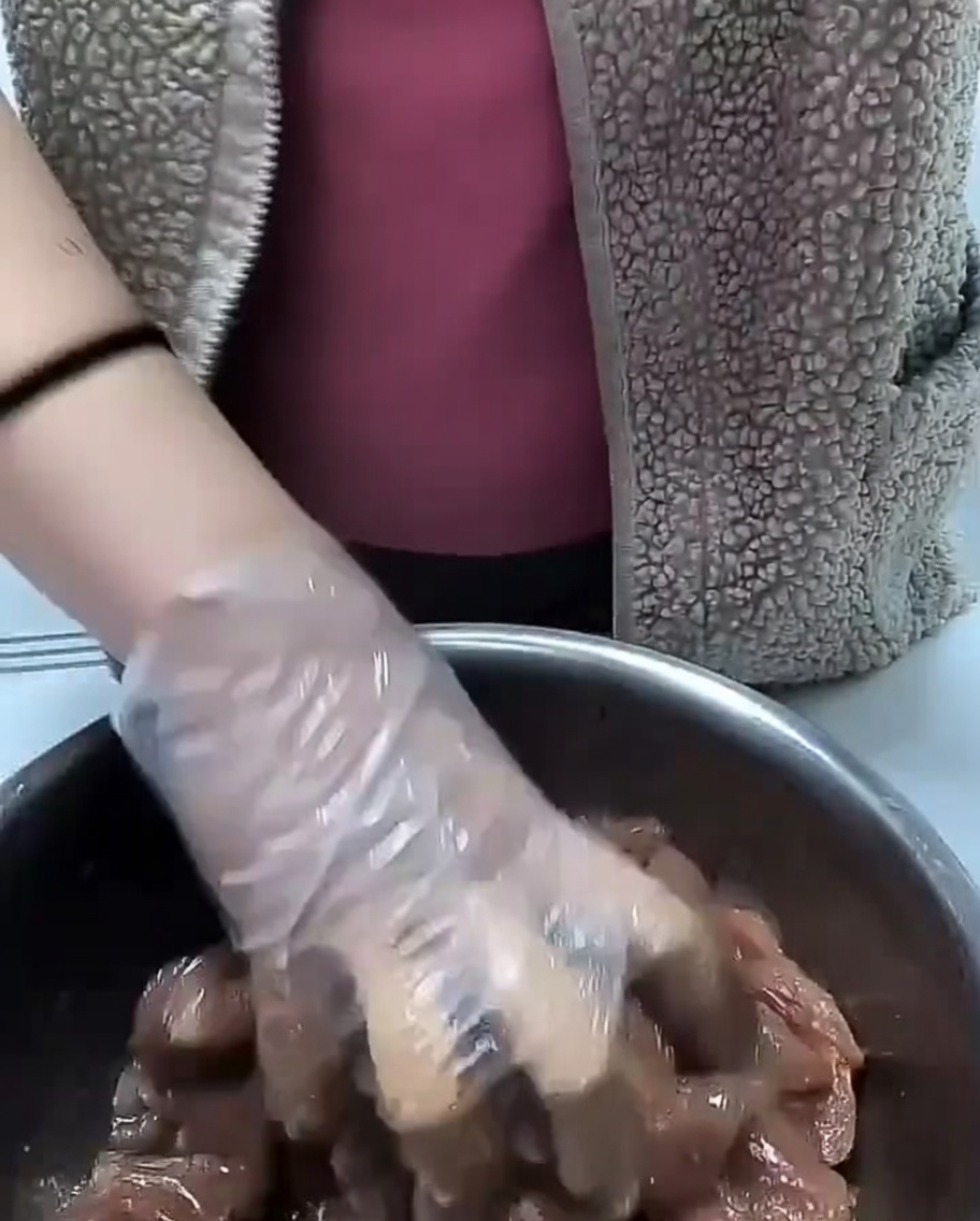 Speiseöl wird über mariniertes Fleisch geträufelt.