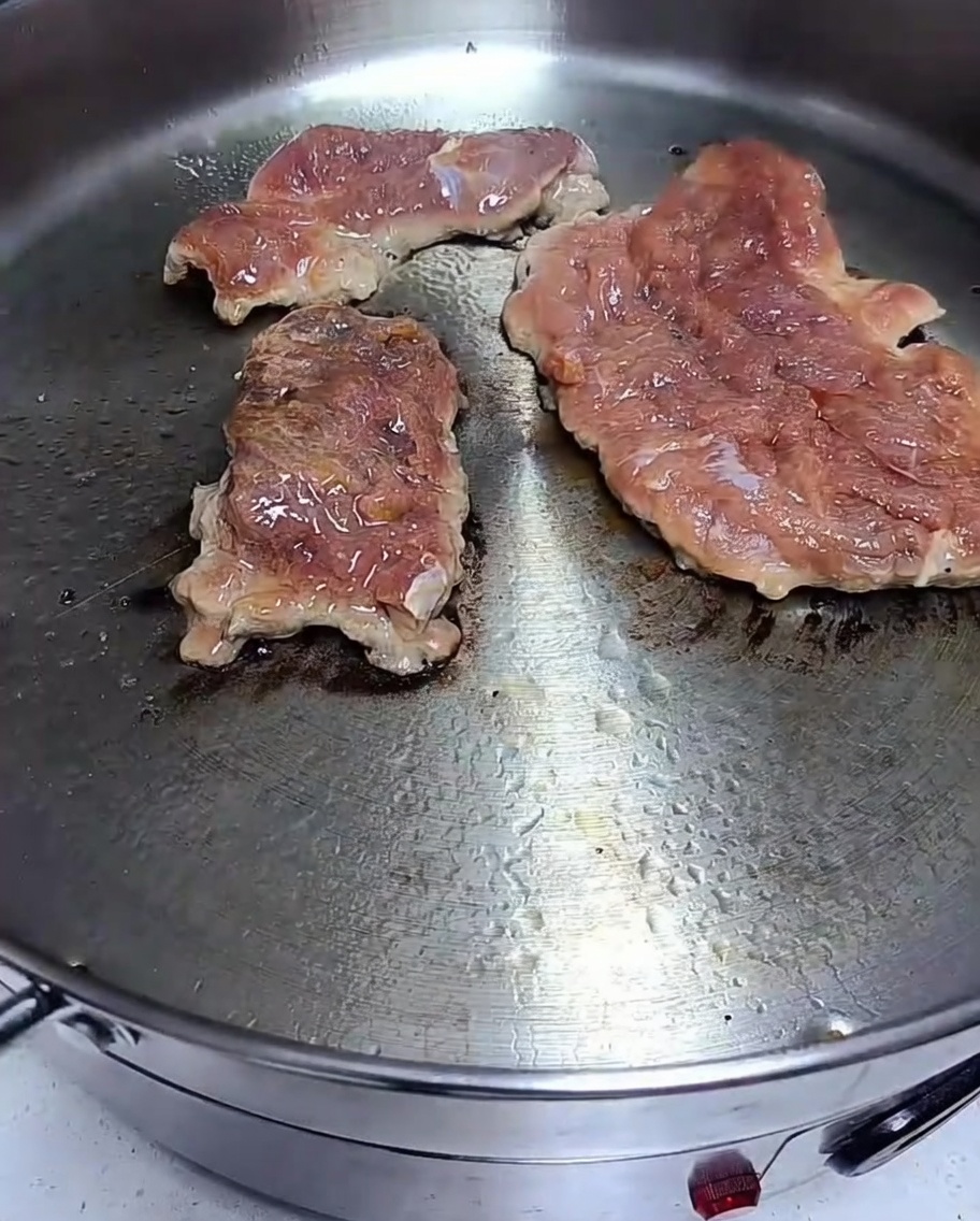 Mariniertes Fleisch brät in einer heißen Pfanne.