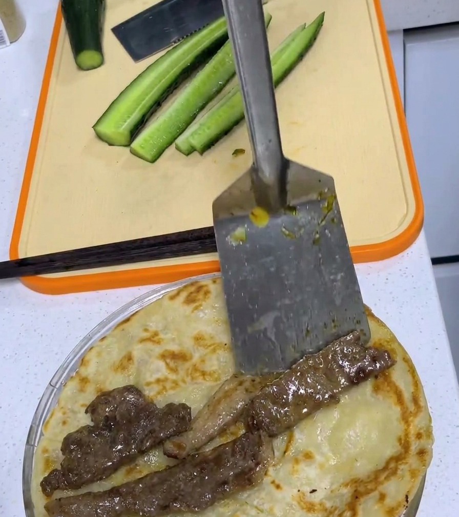 Ein gebratenes Schweinekotelett liegt mittig auf einem Frühlingszwiebel-Pfannkuchen.