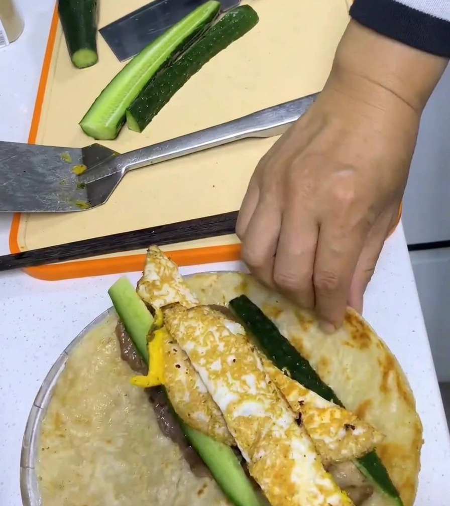 Hände rollen den Wrap fest zusammen.