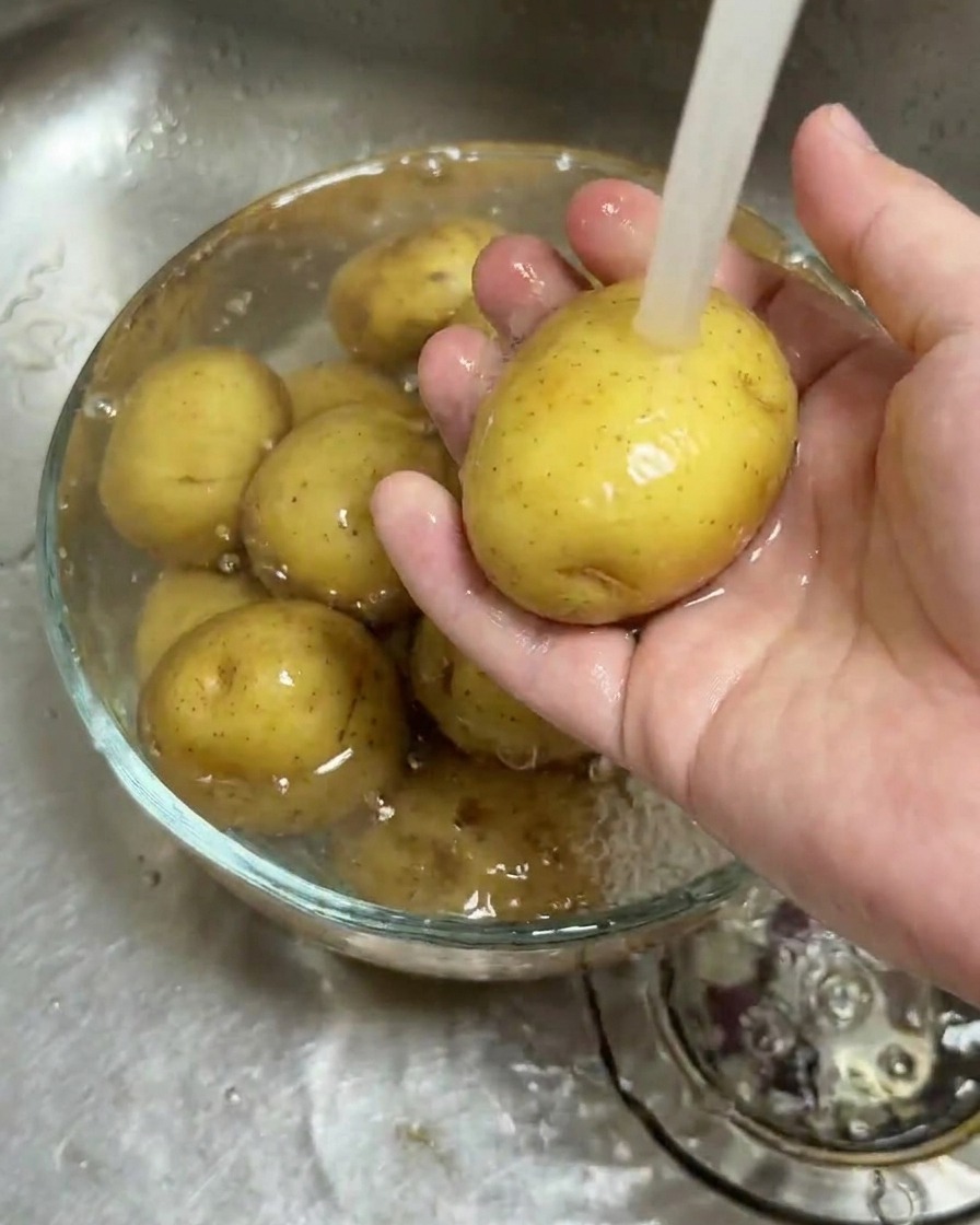 Babykartoffeln werden in einer Glasschüssel unter fließendem Wasser gereinigt.
