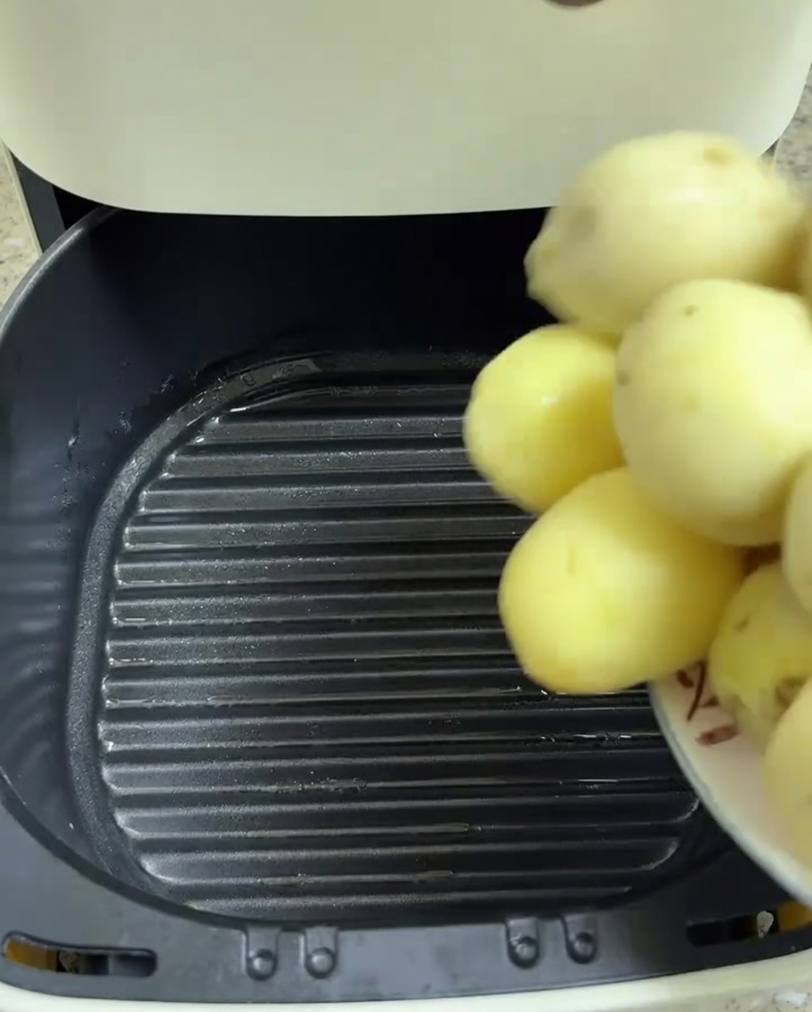 Gepellte Babykartoffeln werden in den Korb der Heißluftfritteuse gelegt.