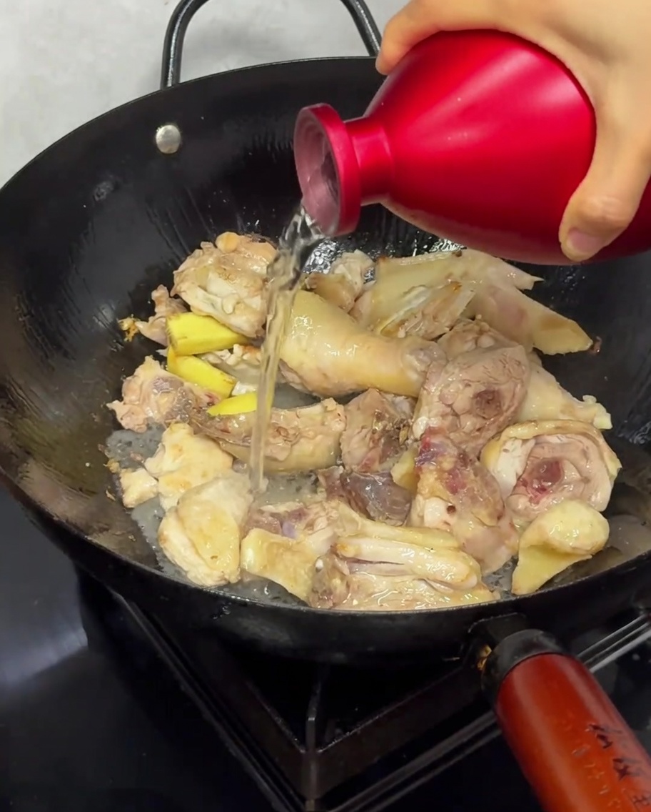 Reiswein wird während des Anbratens über das Huhn im Wok gegossen.