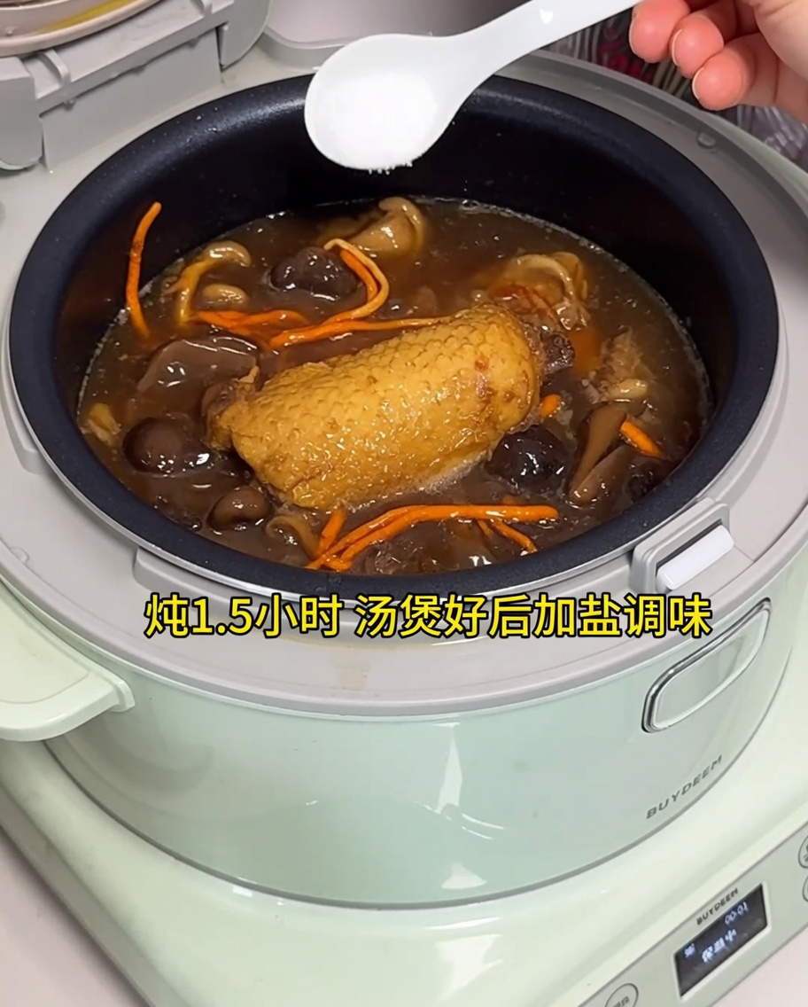 Salz wird zu der fertigen Hühnersuppe im Reiskocher gegeben.