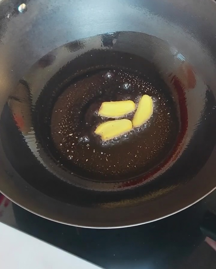 Ingwerscheiben und verschiedene Pilze werden in einem heißen Wok gebraten.