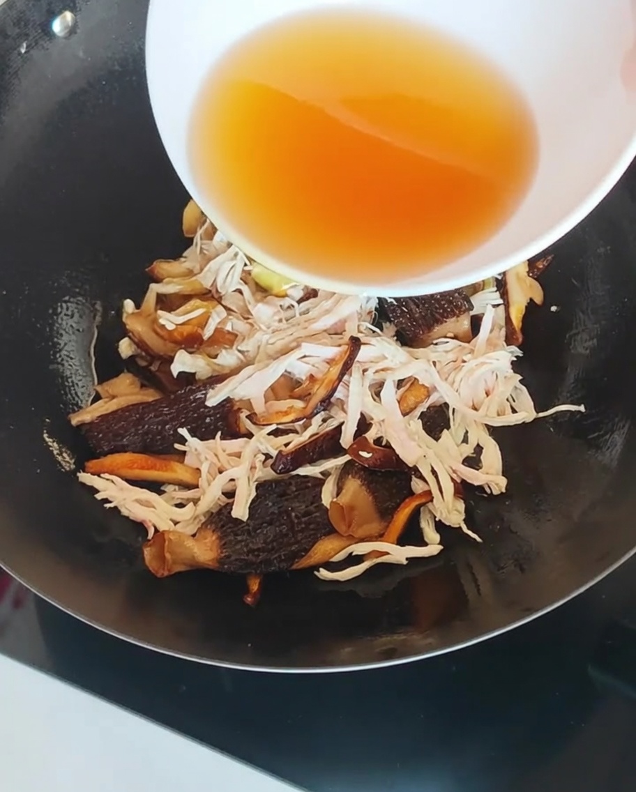 Das gefilterte Pilz-Einweichwasser wird in den Wok gegossen.