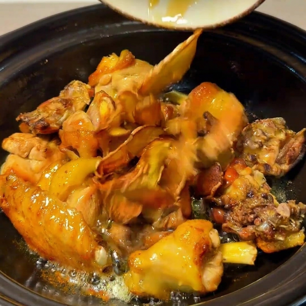 Hähnchen, Pilze, gebratener Ingwer und rote Datteln köcheln zusammen im Tontopf.