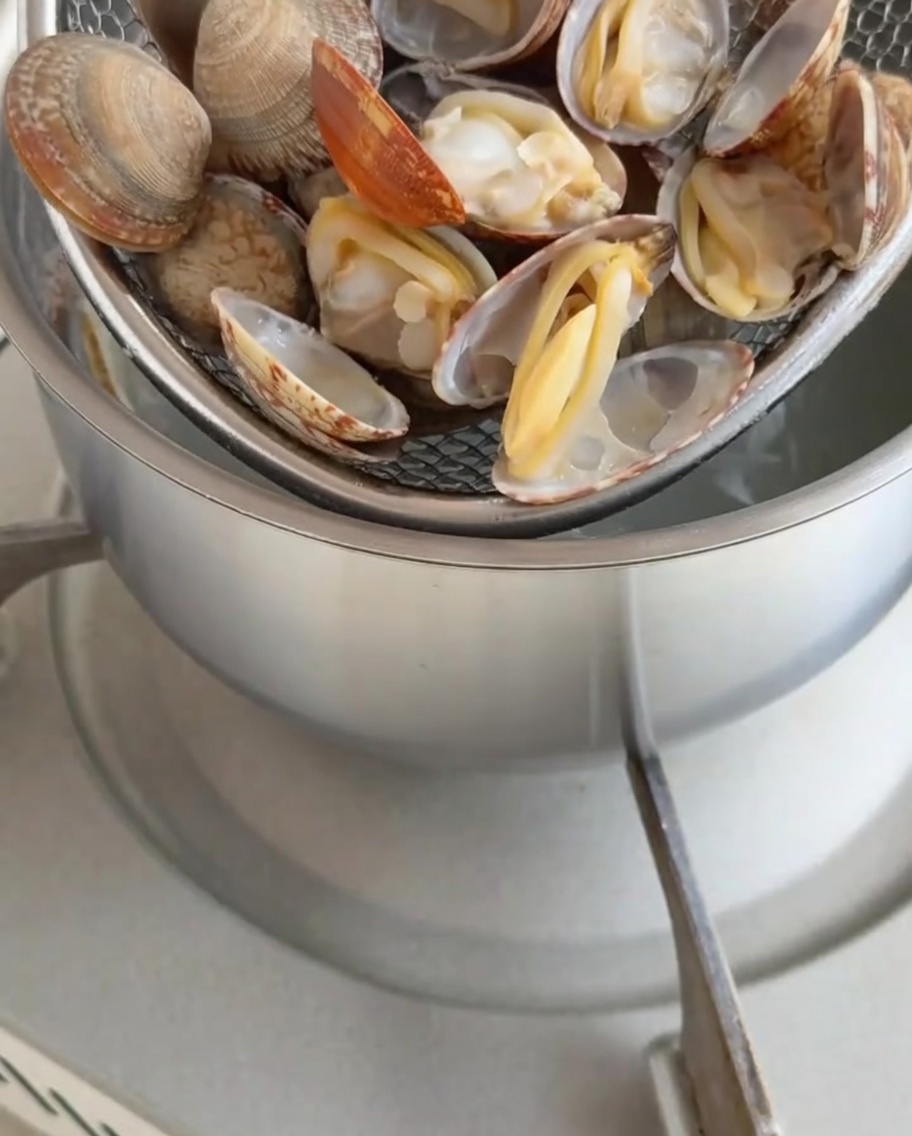 Gekochtes Muschelfleisch wird aus den Schalen gelöst.