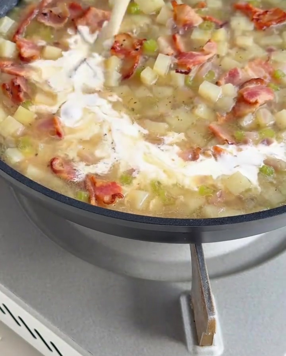 Dicke, cremige weiße Sauce wird in die Pfanne mit der köchelnden Clam Chowder Basis gegossen.